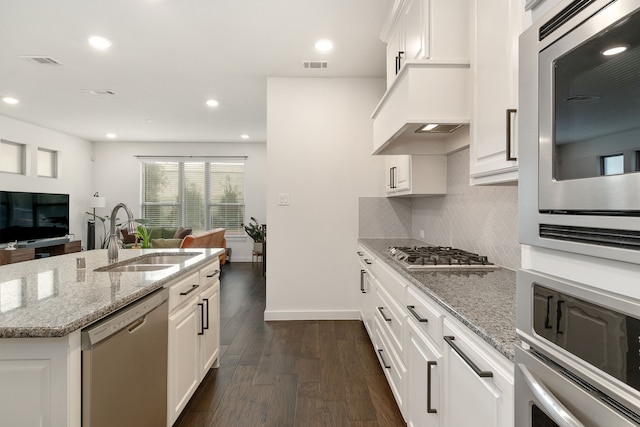 kitchen featuring stainless steel appliances, white cabinetry, light stone countertops, and sink