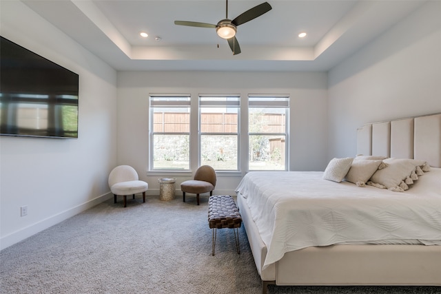 carpeted bedroom featuring ceiling fan and a raised ceiling