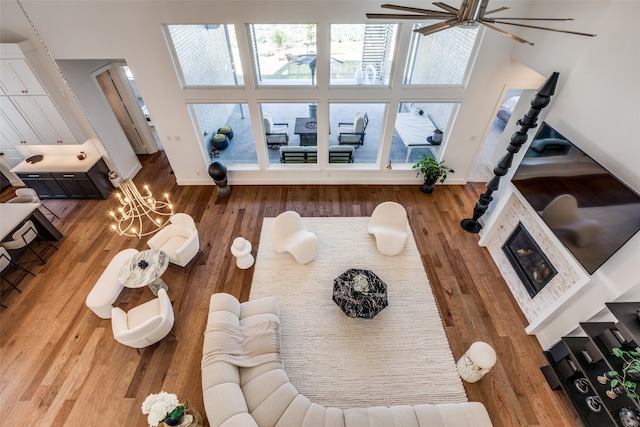 living room featuring ceiling fan with notable chandelier, wood-type flooring, and a high ceiling