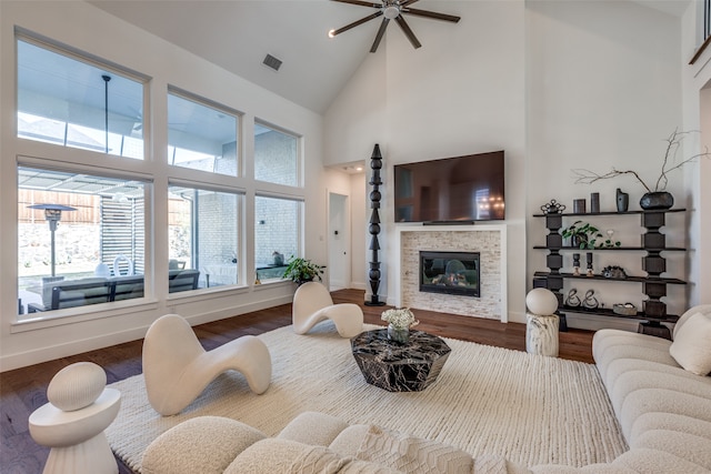 living room with hardwood / wood-style flooring, ceiling fan, a fireplace, and high vaulted ceiling