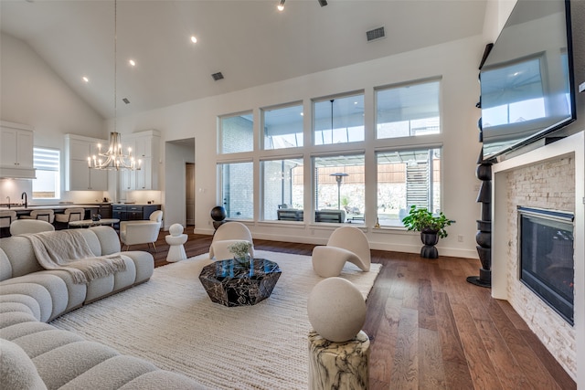 living room featuring a notable chandelier, sink, dark wood-type flooring, and high vaulted ceiling