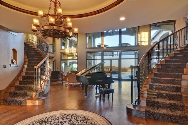 interior space featuring a towering ceiling, dark wood-type flooring, an inviting chandelier, and a tray ceiling