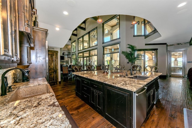 kitchen featuring light stone counters, sink, dark hardwood / wood-style flooring, and an island with sink