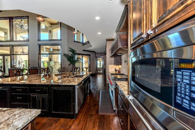 kitchen featuring dark wood-type flooring, stainless steel appliances, sink, and light stone counters