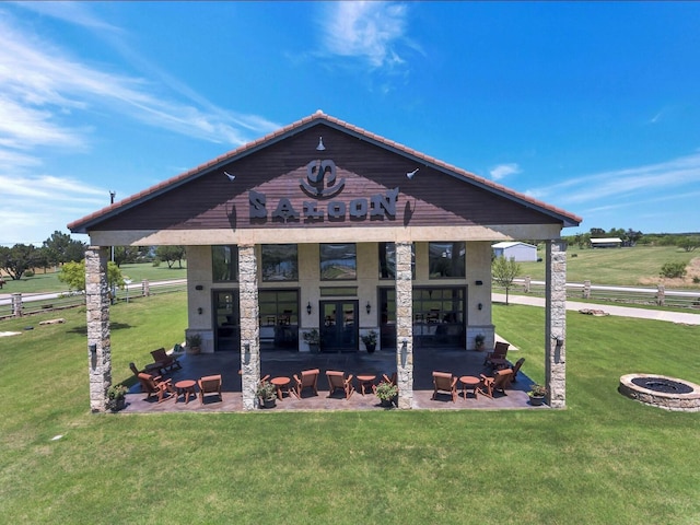 exterior space featuring an outdoor fire pit, a patio area, a lawn, and a rural view