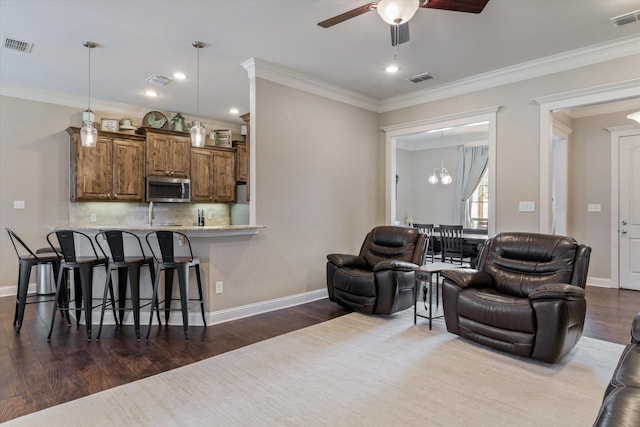 living room featuring ornamental molding, dark hardwood / wood-style flooring, and ceiling fan with notable chandelier