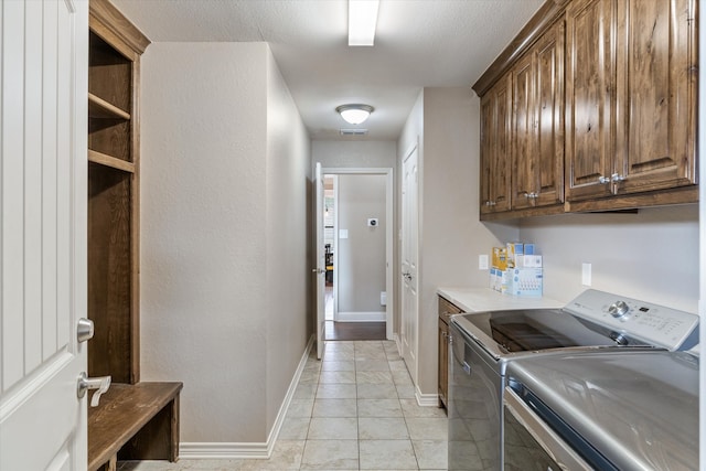 washroom featuring light tile patterned flooring, cabinets, and washer and clothes dryer