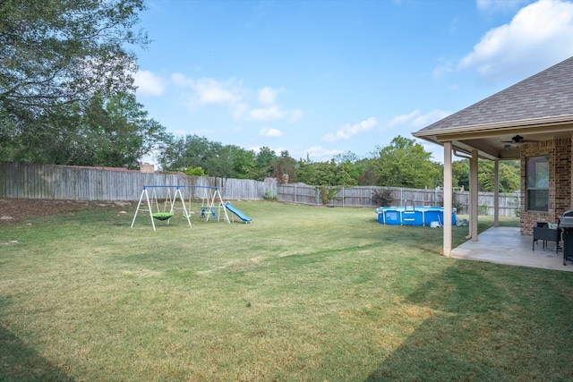 view of yard with a fenced in pool, a patio area, a playground, and ceiling fan