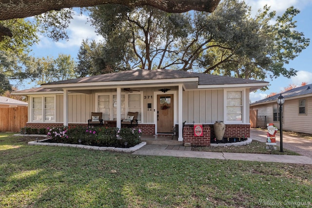 view of front of house with ceiling fan, a front lawn, and covered porch