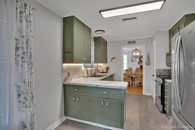 kitchen featuring backsplash, an inviting chandelier, green cabinets, sink, and stainless steel appliances