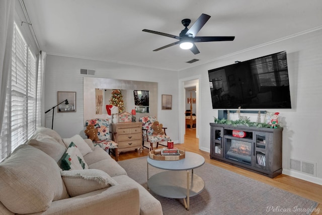 living room featuring ceiling fan, wood-type flooring, and ornamental molding