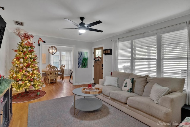 living room with ceiling fan, crown molding, and light wood-type flooring