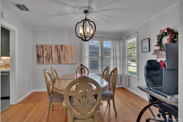 dining area with light wood-type flooring, crown molding, and an inviting chandelier