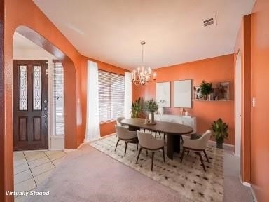 dining area with light carpet and a notable chandelier