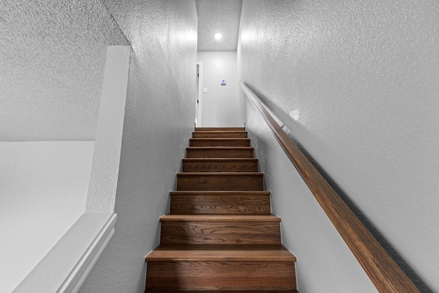 staircase featuring a textured ceiling