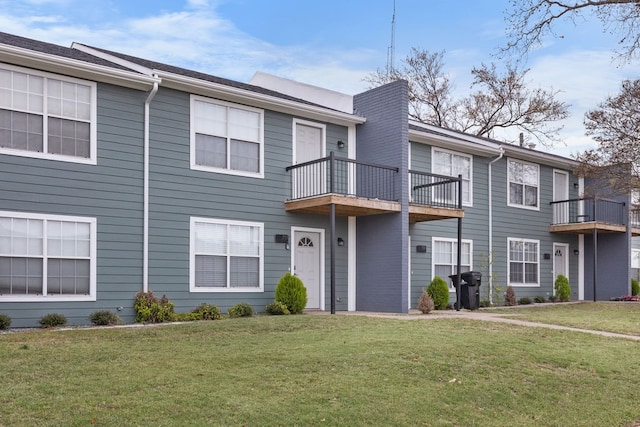 view of property with a balcony and a front yard