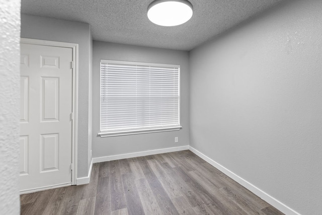 empty room featuring wood-type flooring and a textured ceiling