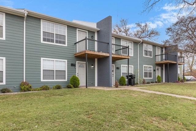 view of property with a balcony and a front lawn