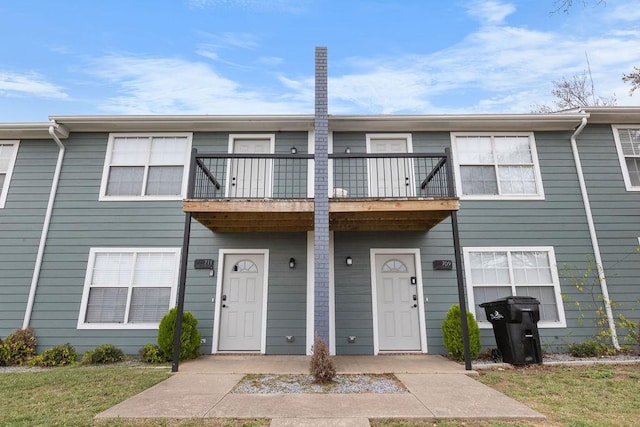 view of property with a balcony and a front yard