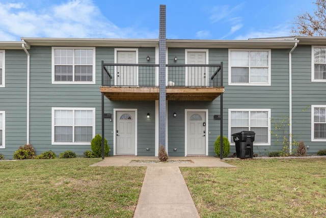 view of property featuring a front yard and a balcony