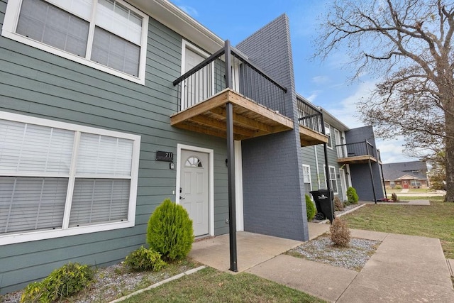 view of exterior entry featuring a balcony and a yard