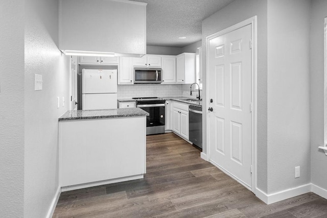 kitchen featuring stainless steel appliances, dark wood-type flooring, white cabinets, and decorative backsplash