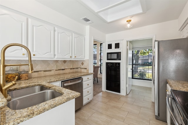 kitchen with light stone countertops, appliances with stainless steel finishes, tasteful backsplash, sink, and white cabinets