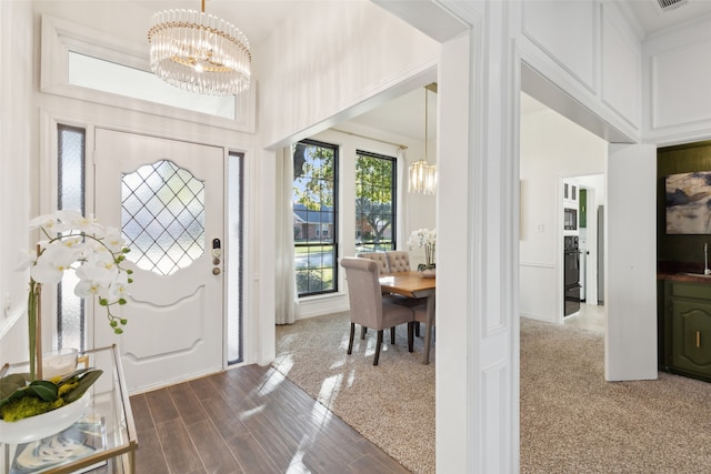 foyer featuring carpet flooring, a notable chandelier, and sink