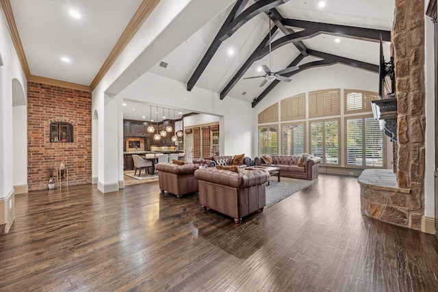 living room featuring dark hardwood / wood-style flooring, ornamental molding, beam ceiling, high vaulted ceiling, and a fireplace