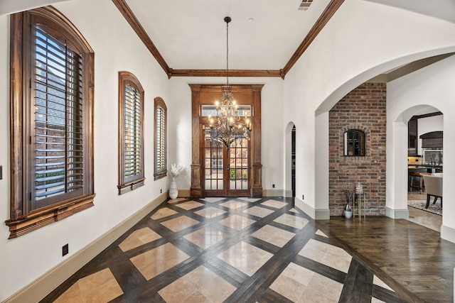 entryway with french doors, ornamental molding, and a notable chandelier