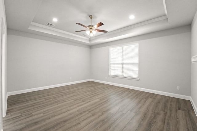 unfurnished room with crown molding, dark wood-type flooring, and a tray ceiling