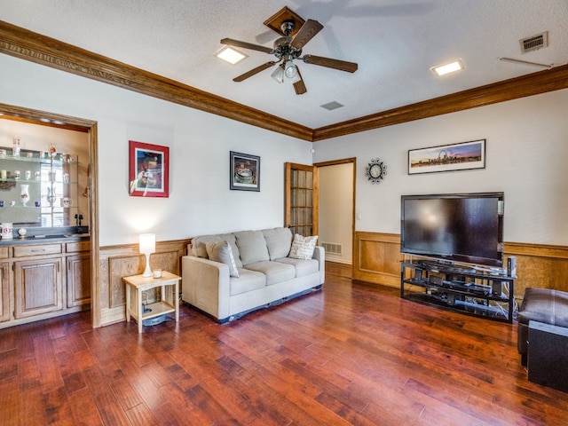 living room featuring dark wood-type flooring, a textured ceiling, and ornamental molding