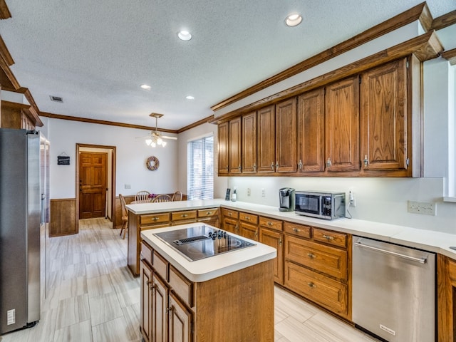 kitchen with appliances with stainless steel finishes, a center island, a textured ceiling, and ornamental molding