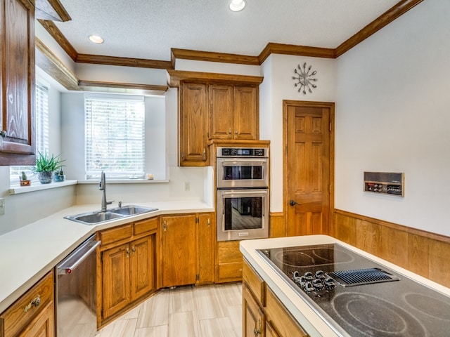 kitchen featuring sink, crown molding, a textured ceiling, wooden walls, and appliances with stainless steel finishes