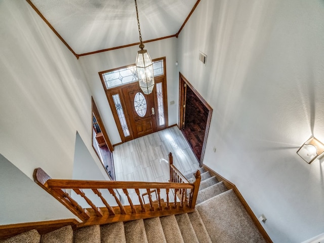 foyer entrance featuring a chandelier, high vaulted ceiling, and crown molding