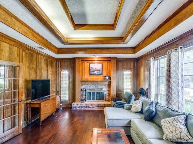 living room with dark hardwood / wood-style floors, a fireplace, ornamental molding, a textured ceiling, and a raised ceiling