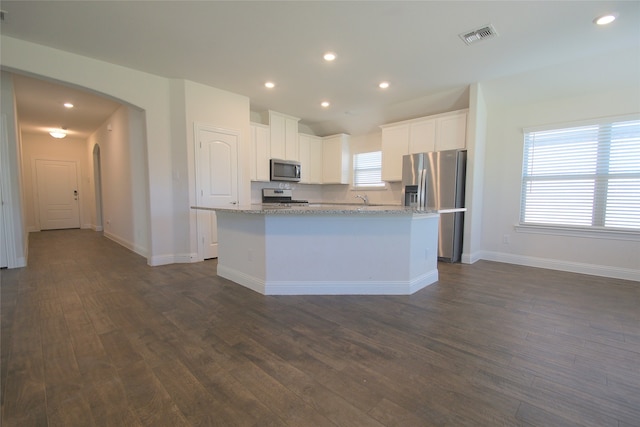 kitchen with a kitchen island with sink, dark wood-type flooring, white cabinets, appliances with stainless steel finishes, and light stone counters