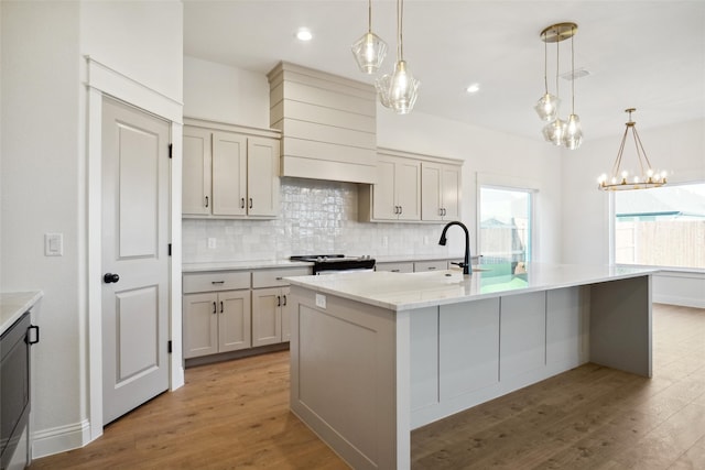 kitchen with hanging light fixtures, a center island with sink, and light wood-type flooring