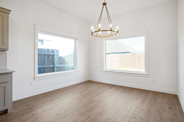 unfurnished dining area featuring a notable chandelier and light hardwood / wood-style flooring