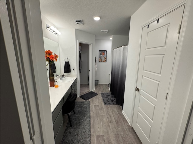 bathroom with hardwood / wood-style flooring, vanity, and a textured ceiling