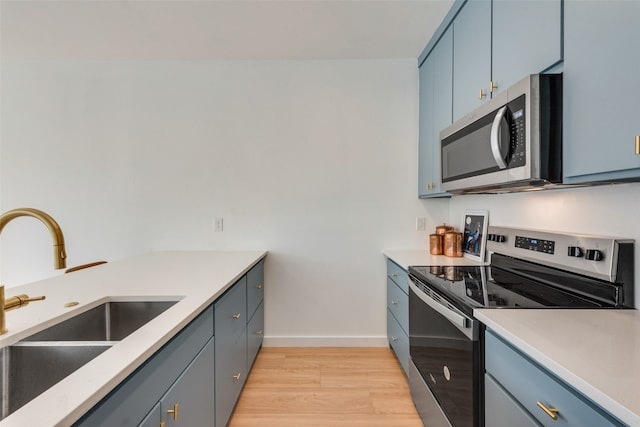 kitchen featuring blue cabinetry, stainless steel appliances, light hardwood / wood-style floors, and sink