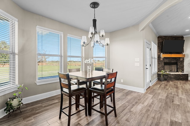 dining room with wood-type flooring, a stone fireplace, and a healthy amount of sunlight