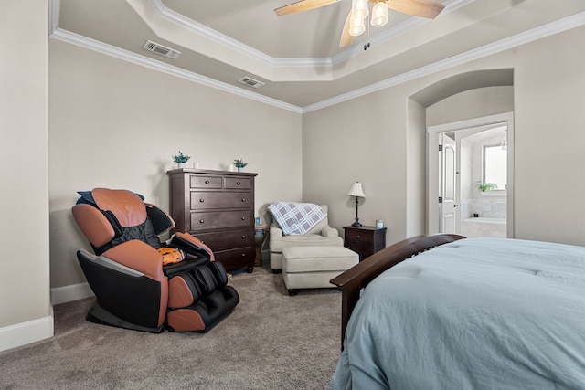 carpeted bedroom featuring a tray ceiling, ensuite bath, ceiling fan, and ornamental molding