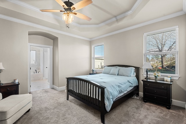 bedroom featuring ensuite bath, ornamental molding, a raised ceiling, ceiling fan, and carpet floors