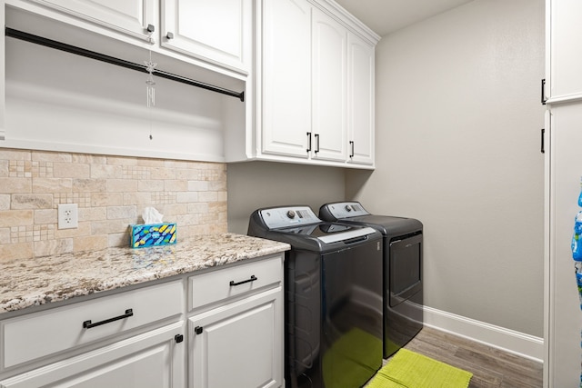 clothes washing area with cabinets, hardwood / wood-style flooring, and washing machine and clothes dryer