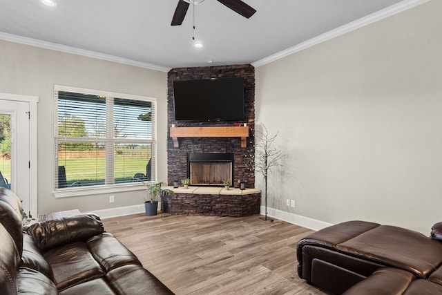 living room with a stone fireplace, ceiling fan, light hardwood / wood-style flooring, and ornamental molding