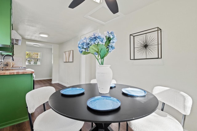 dining room with ceiling fan, sink, and dark wood-type flooring