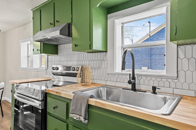 kitchen featuring backsplash, green cabinets, plenty of natural light, and stainless steel electric range