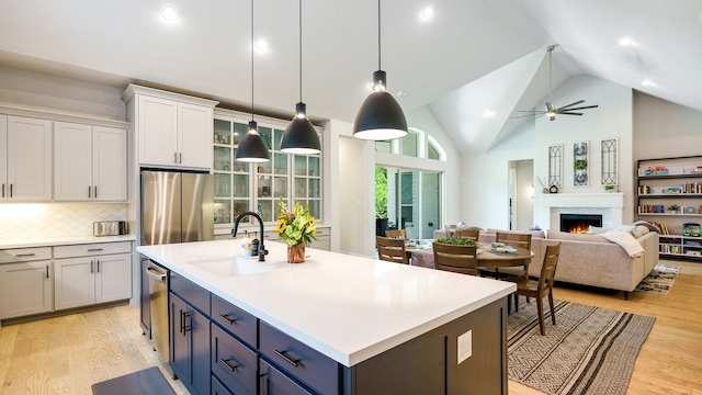 kitchen featuring white cabinets, sink, light hardwood / wood-style flooring, an island with sink, and stainless steel appliances