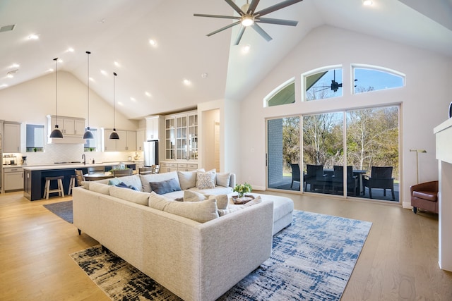 living room featuring ceiling fan, high vaulted ceiling, and light hardwood / wood-style floors